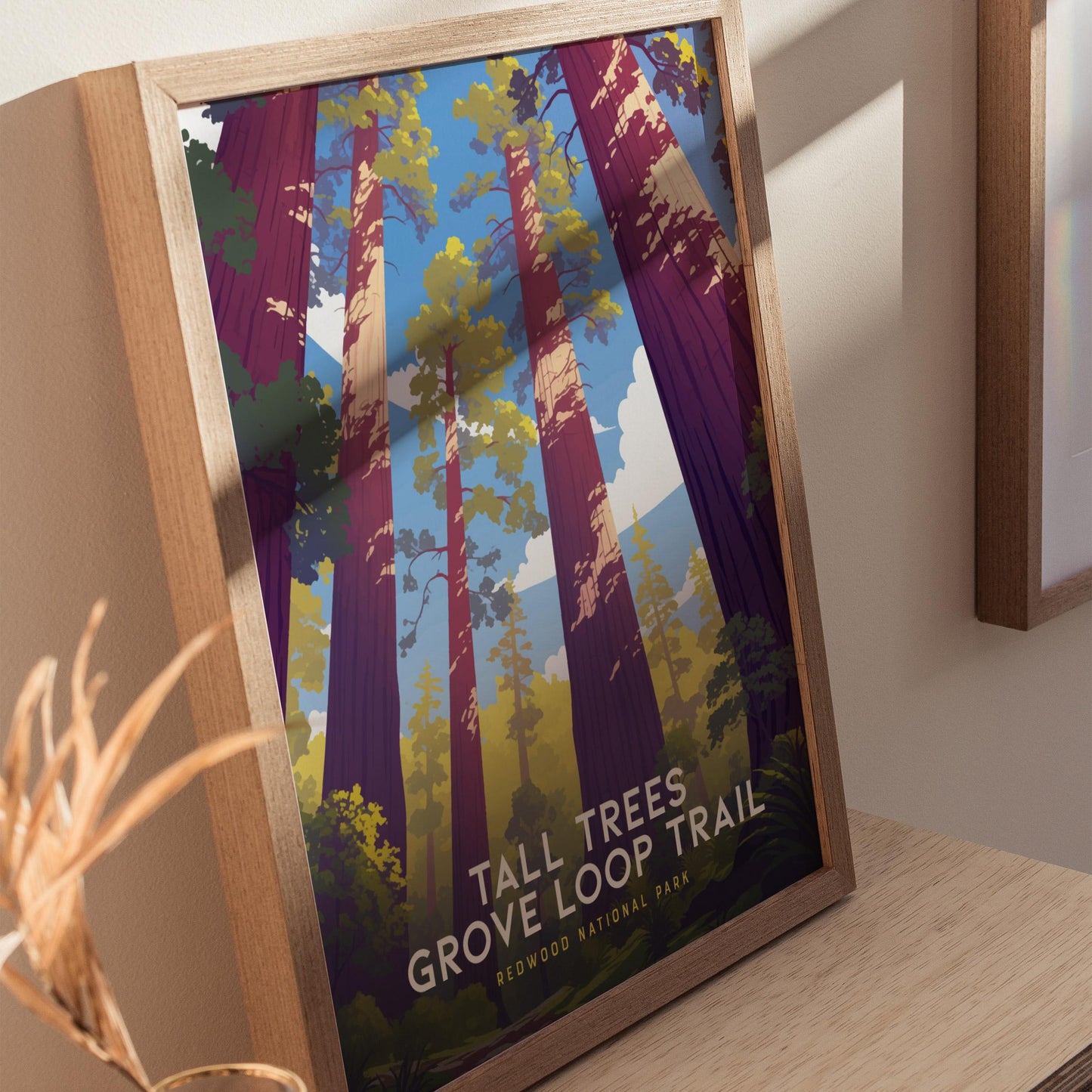 Framed poster of a forest design with 'Tall Trees Grove Loop Trail' text on a wooden surface.