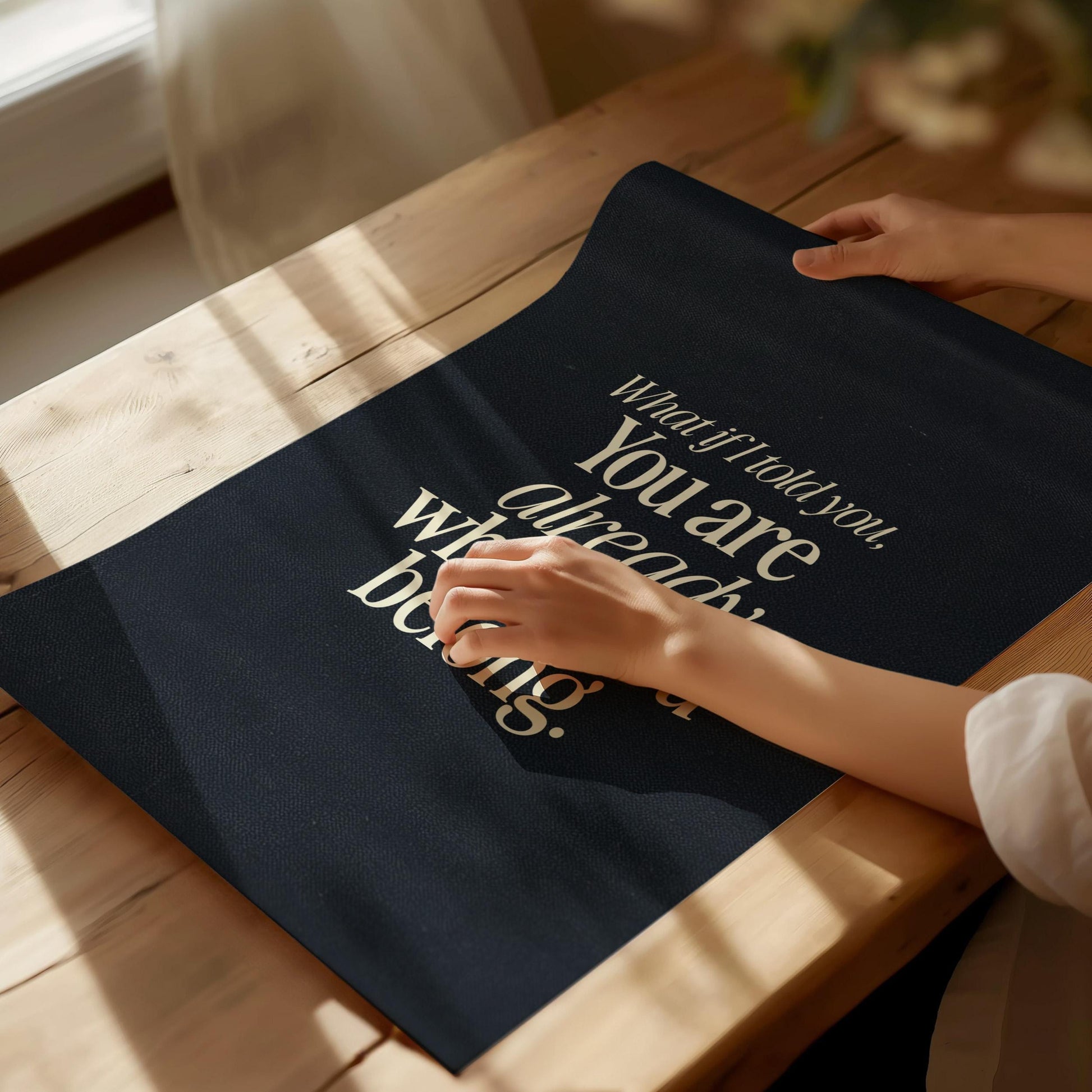Person holding a black poster with a motivational quote on a wooden table.