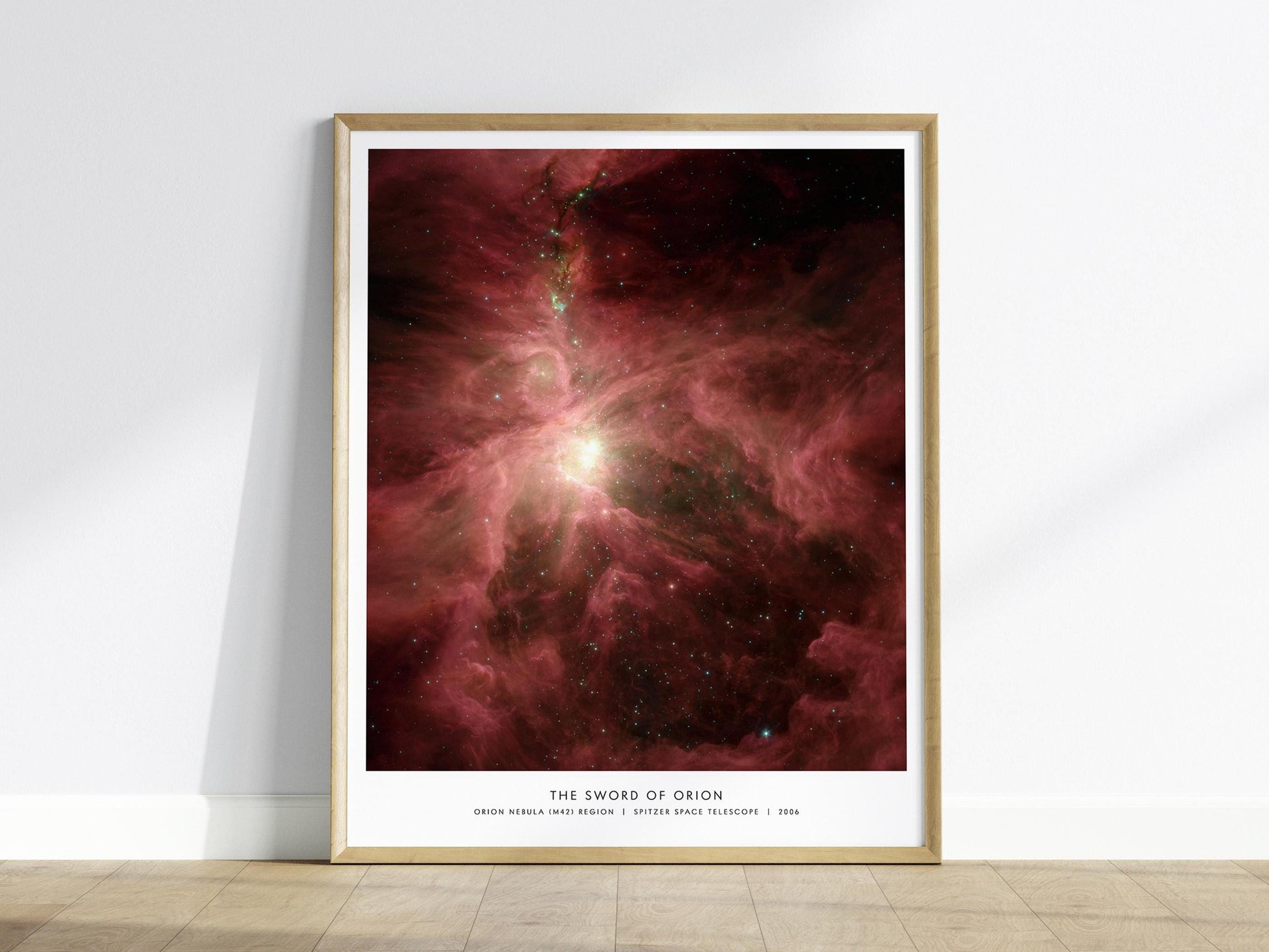 Framed space-themed poster of The Sword of Orion nebula on a white wall.