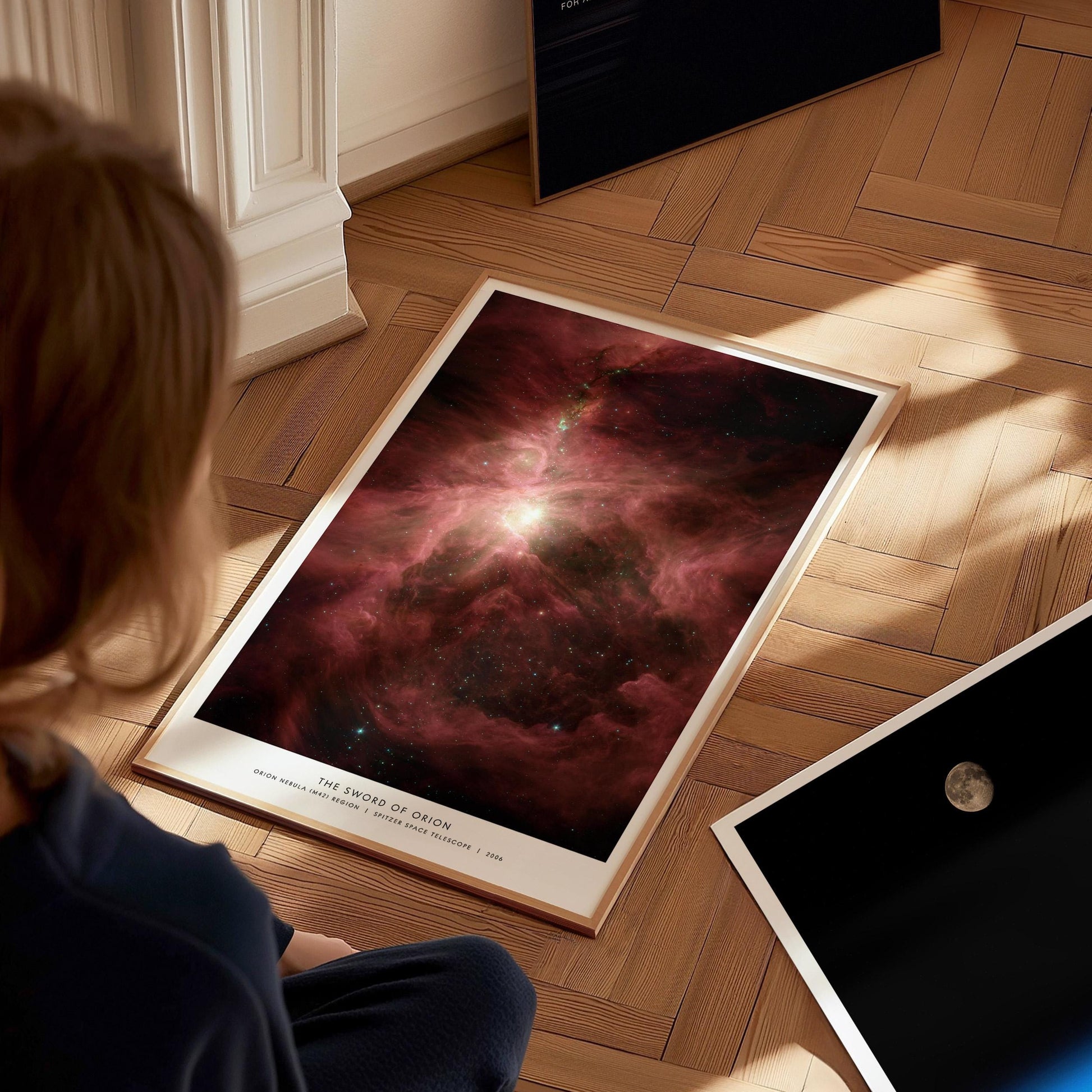 Person looking at a large space nebula poster on a wooden floor