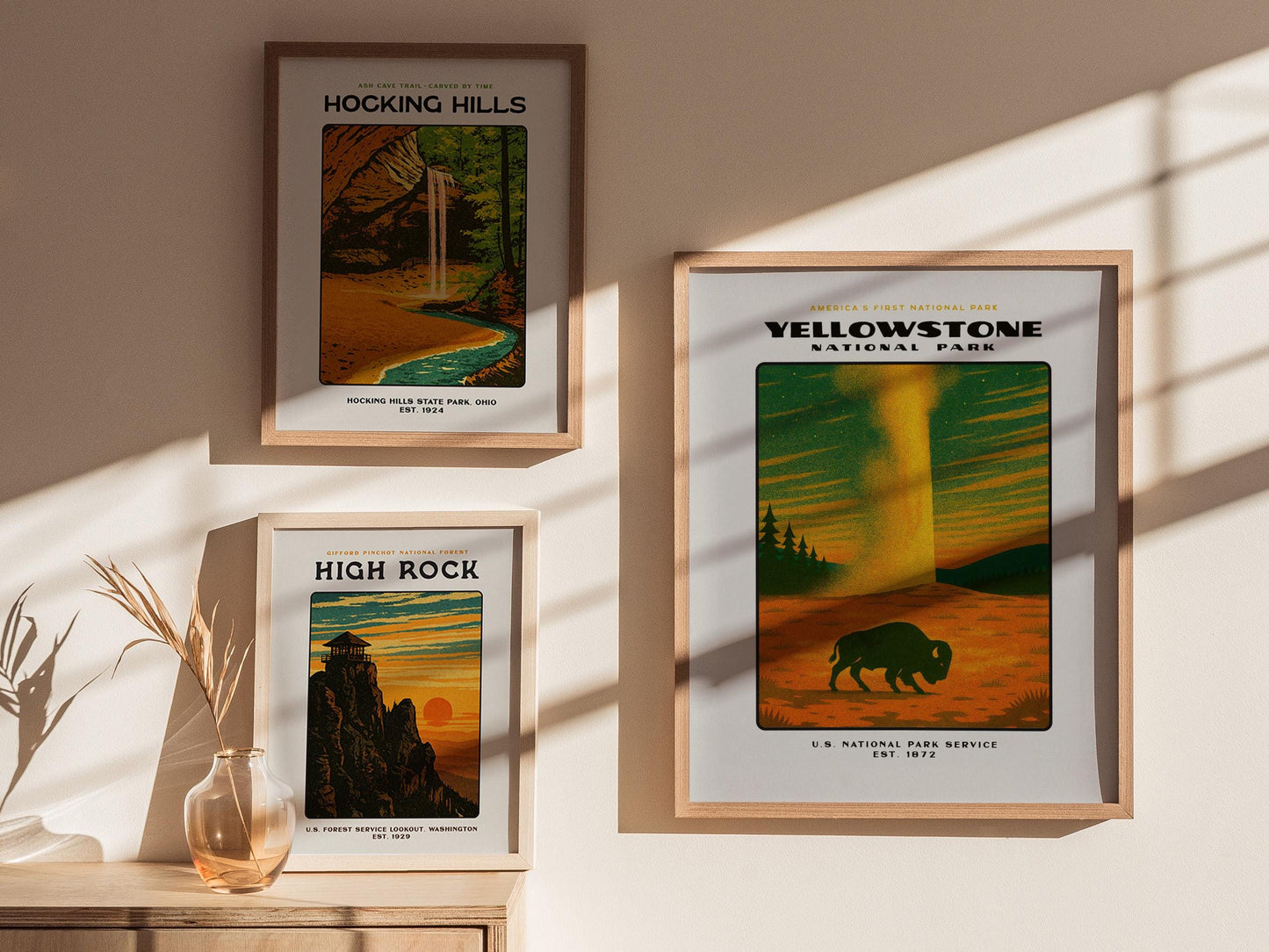 Three framed posters of national parks on a wall with sunlight casting shadows.