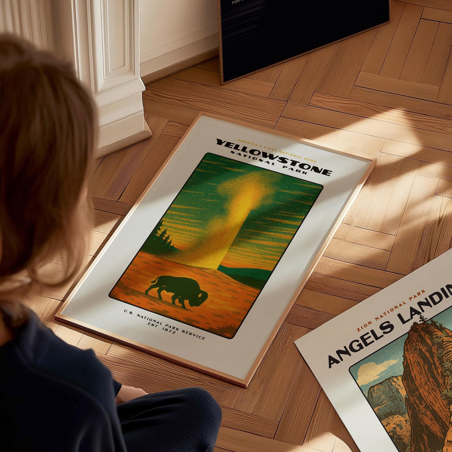 Person looking at Yellowstone National Park poster on a wooden floor