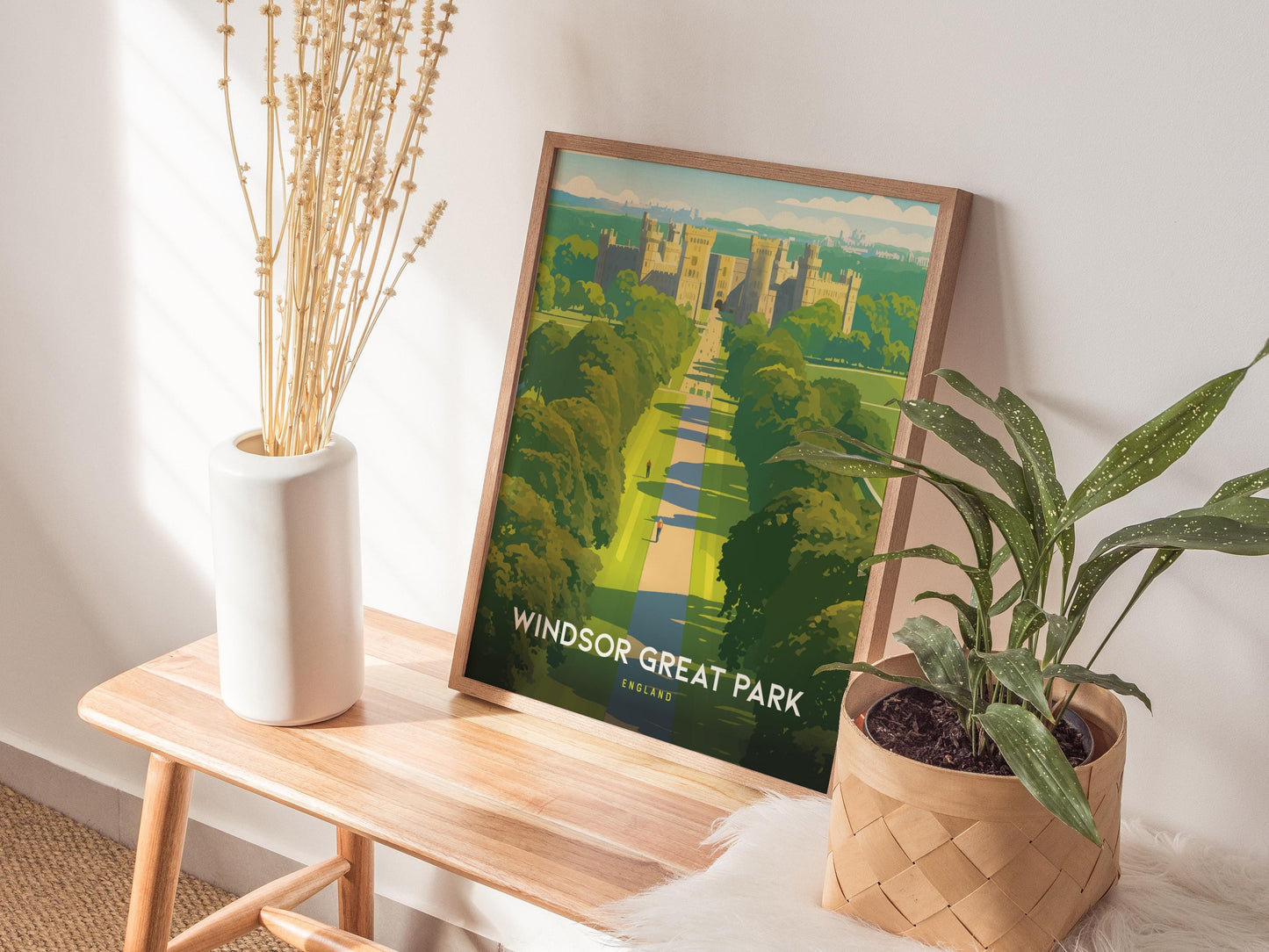Framed poster of Windsor Great Park on a wooden table with plants and a vase.