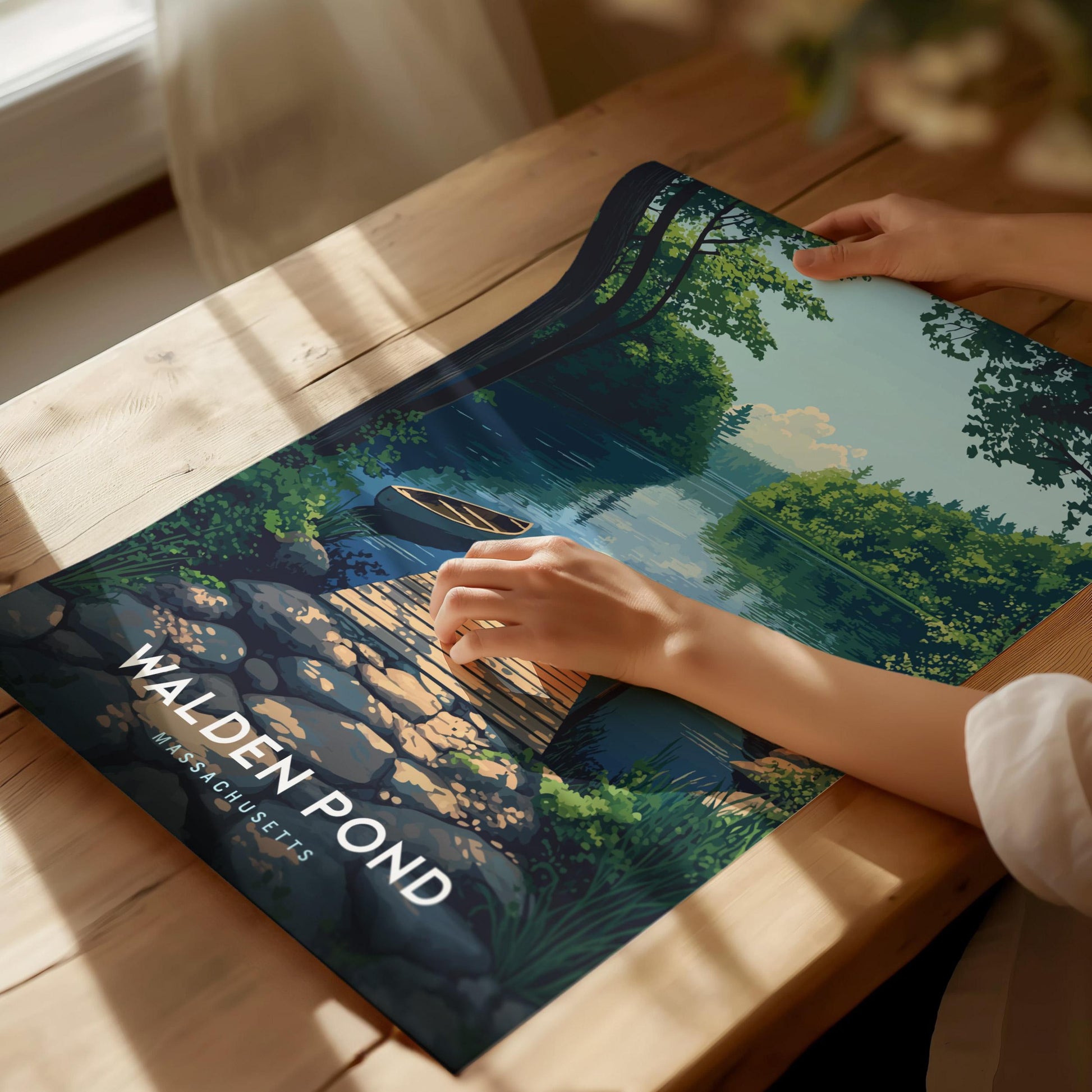 Person holding a scenic poster with Walden Pond design on a wooden table.