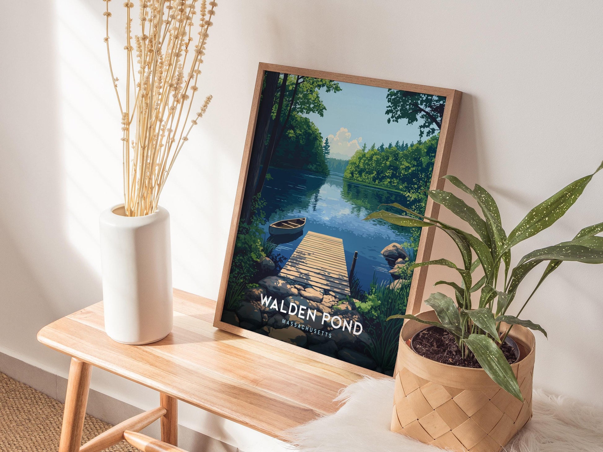 Framed artwork of Walden Pond on a wooden table with plants and a vase.