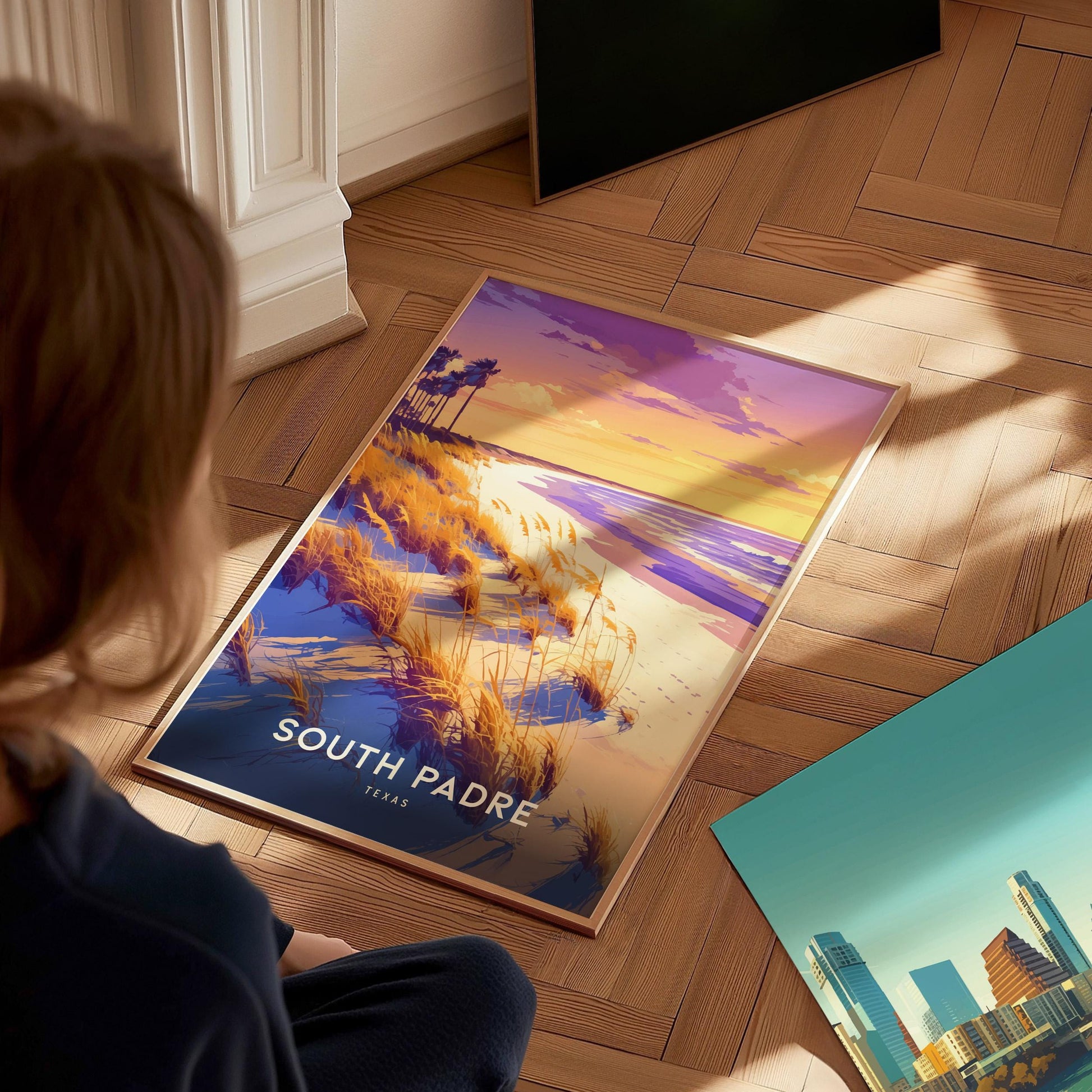 Person looking at a 'South Padre Island' poster on a wooden floor
