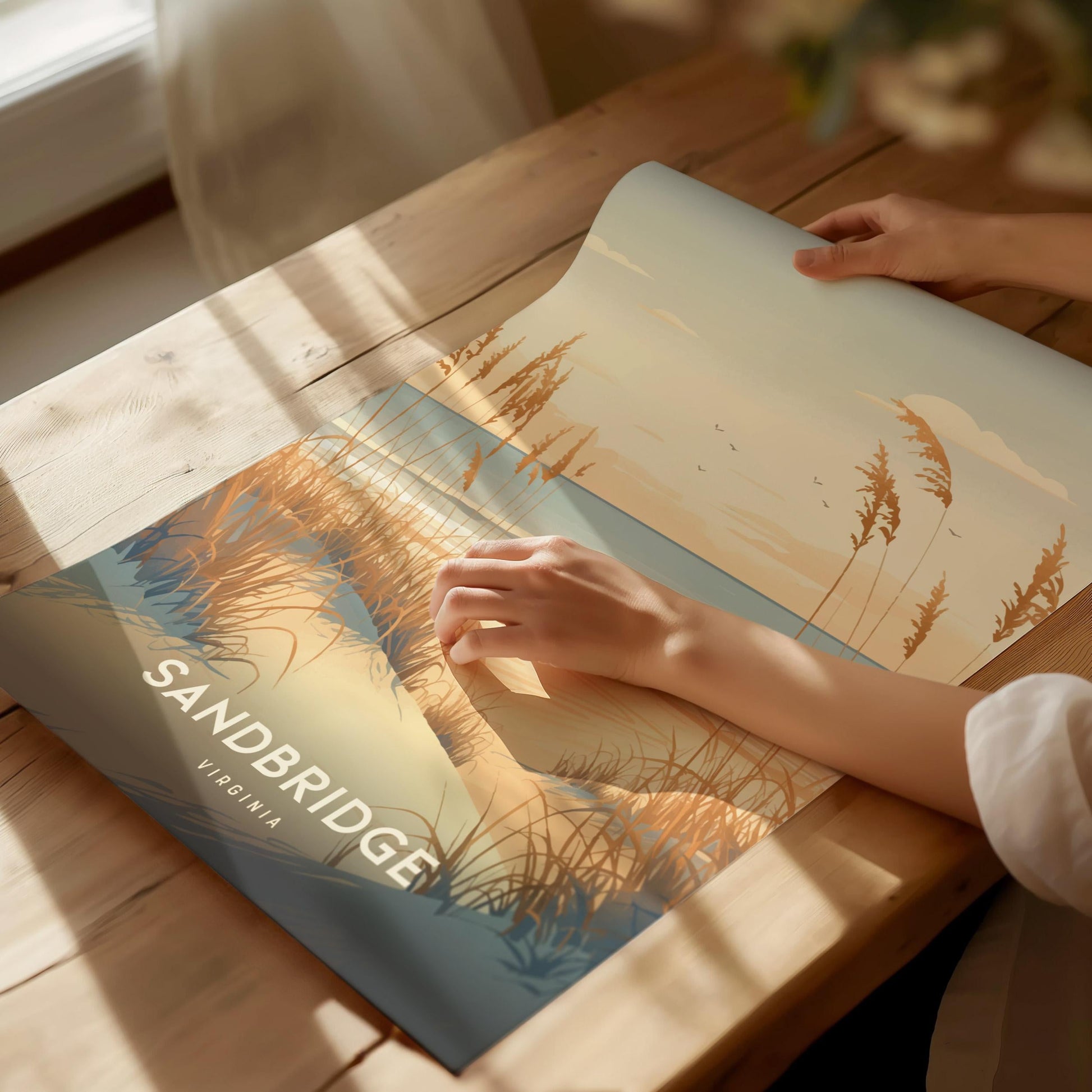 Person holding a scenic poster of Sandbridge, Virginia on a wooden table.