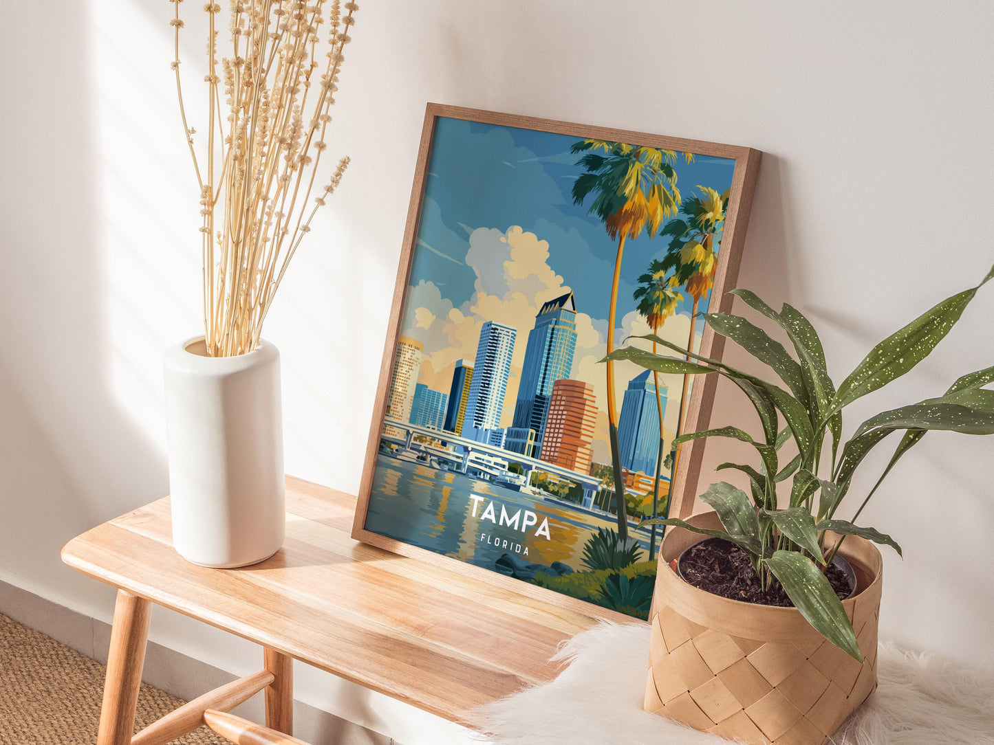Framed poster of Tampa, Florida on a wooden table with plants and a vase.