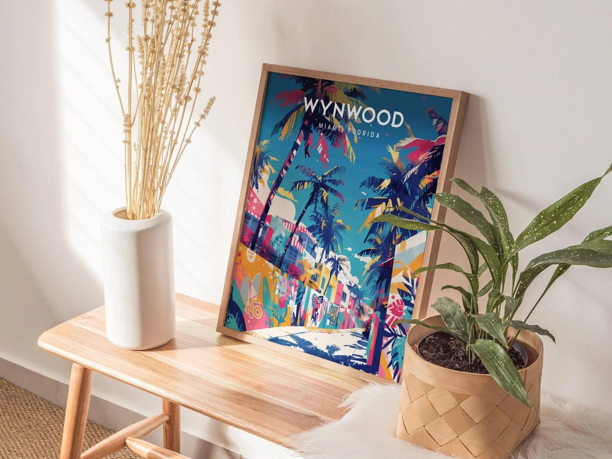 Colorful Wynwood art print on a wooden table with plants and a vase.