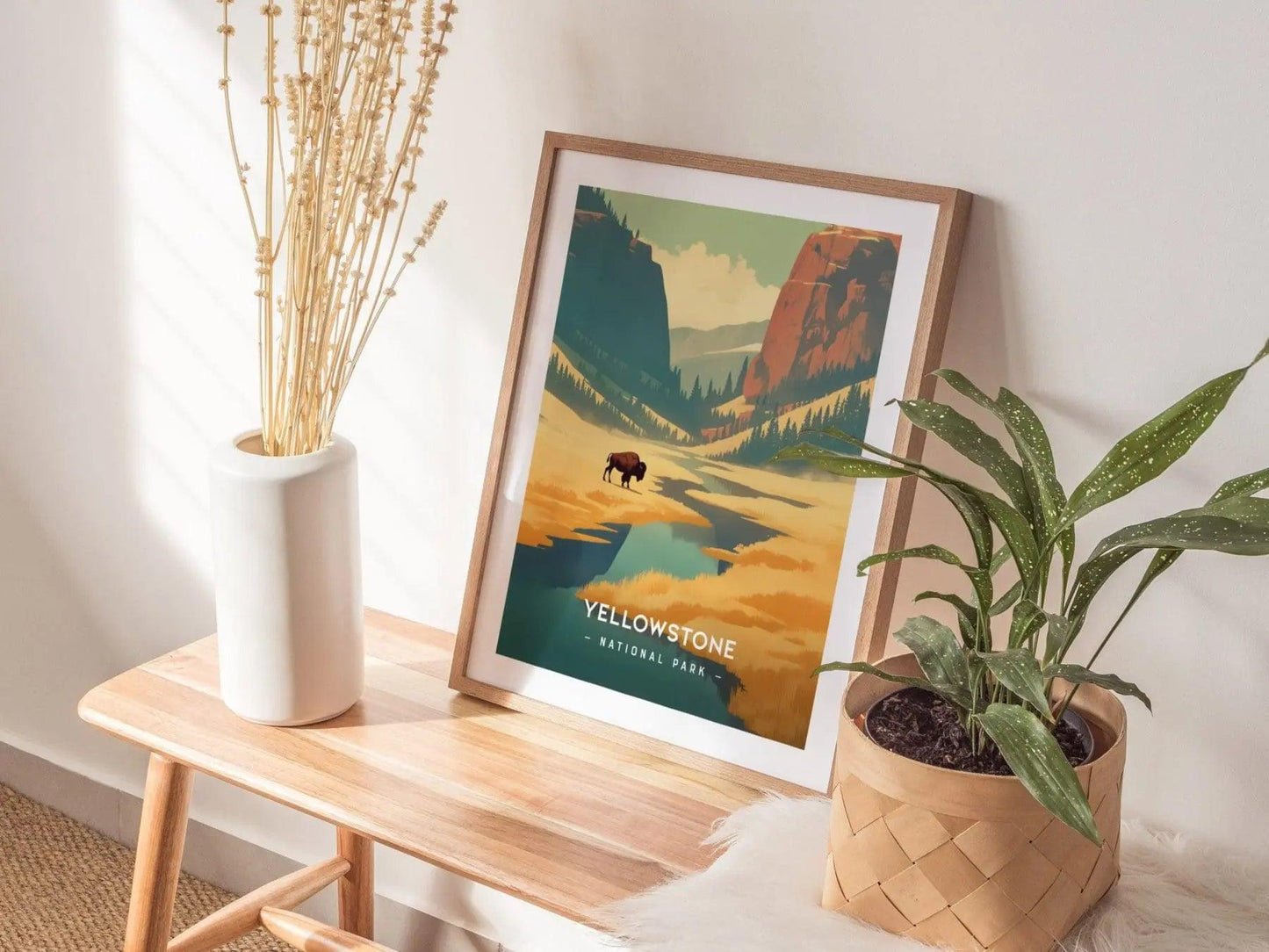 Framed Yellowstone National Park poster on a wooden table with plants and a vase.