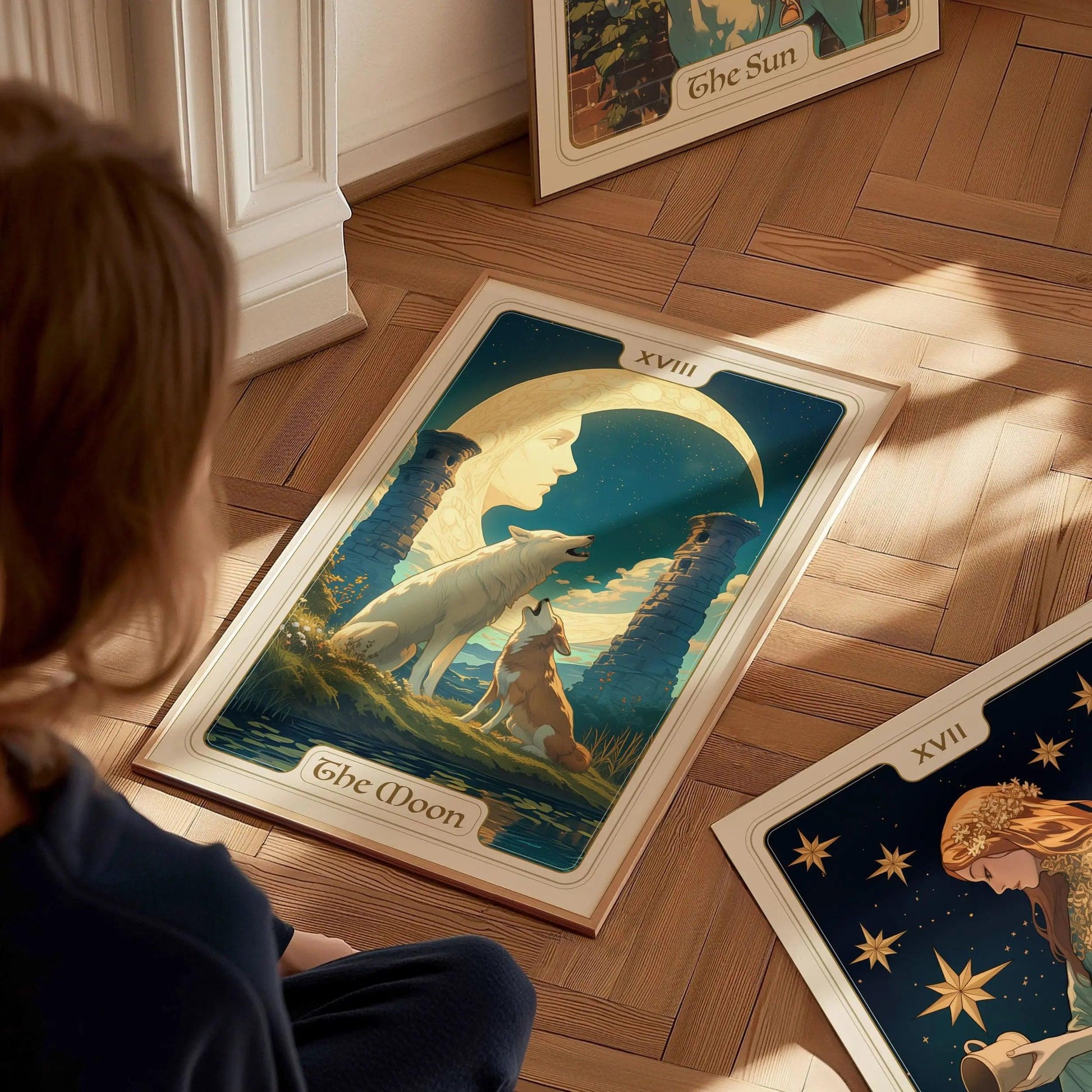 Person looking at a tarot card poster for The Moon featuring two wolves under a moonlit sky on a wooden floor.