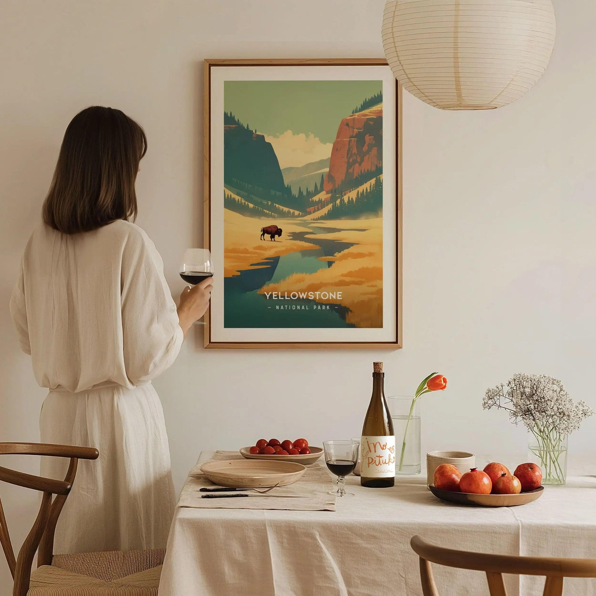 Woman in a white dress standing in a dining room with a framed Yellowstone poster on the wall.