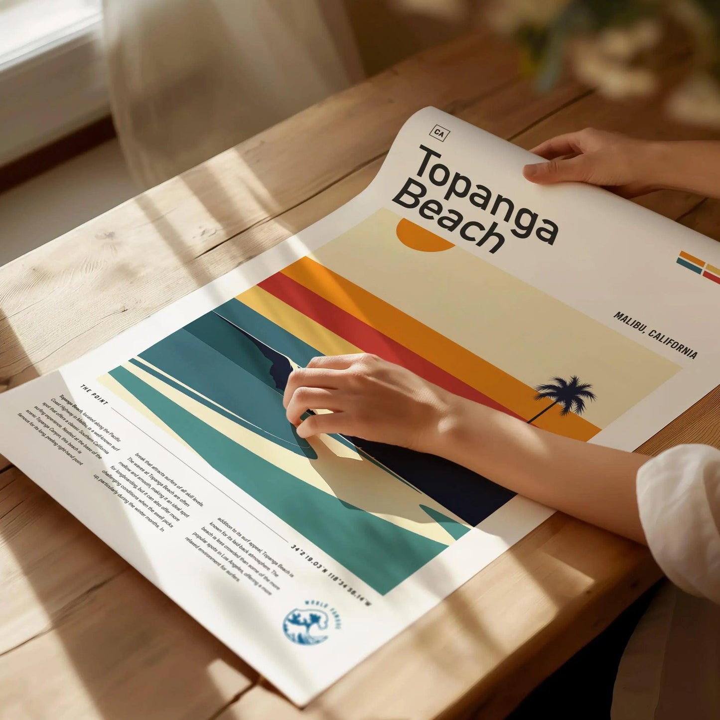 Person holding a poster with 'Topanga Beach' cover on a wooden table