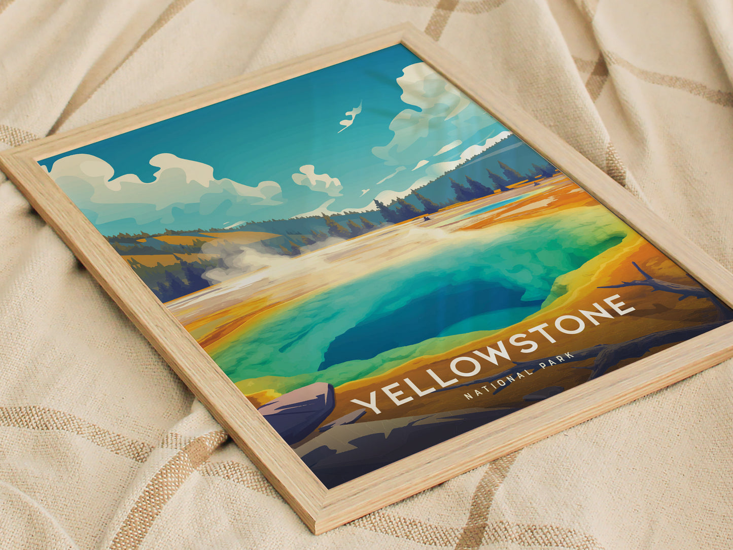 A framed poster of Yellowstone National Parks Morning Glory Pool, showcasing vibrant blue, green, and golden hues, rests on a textured beige fabric.