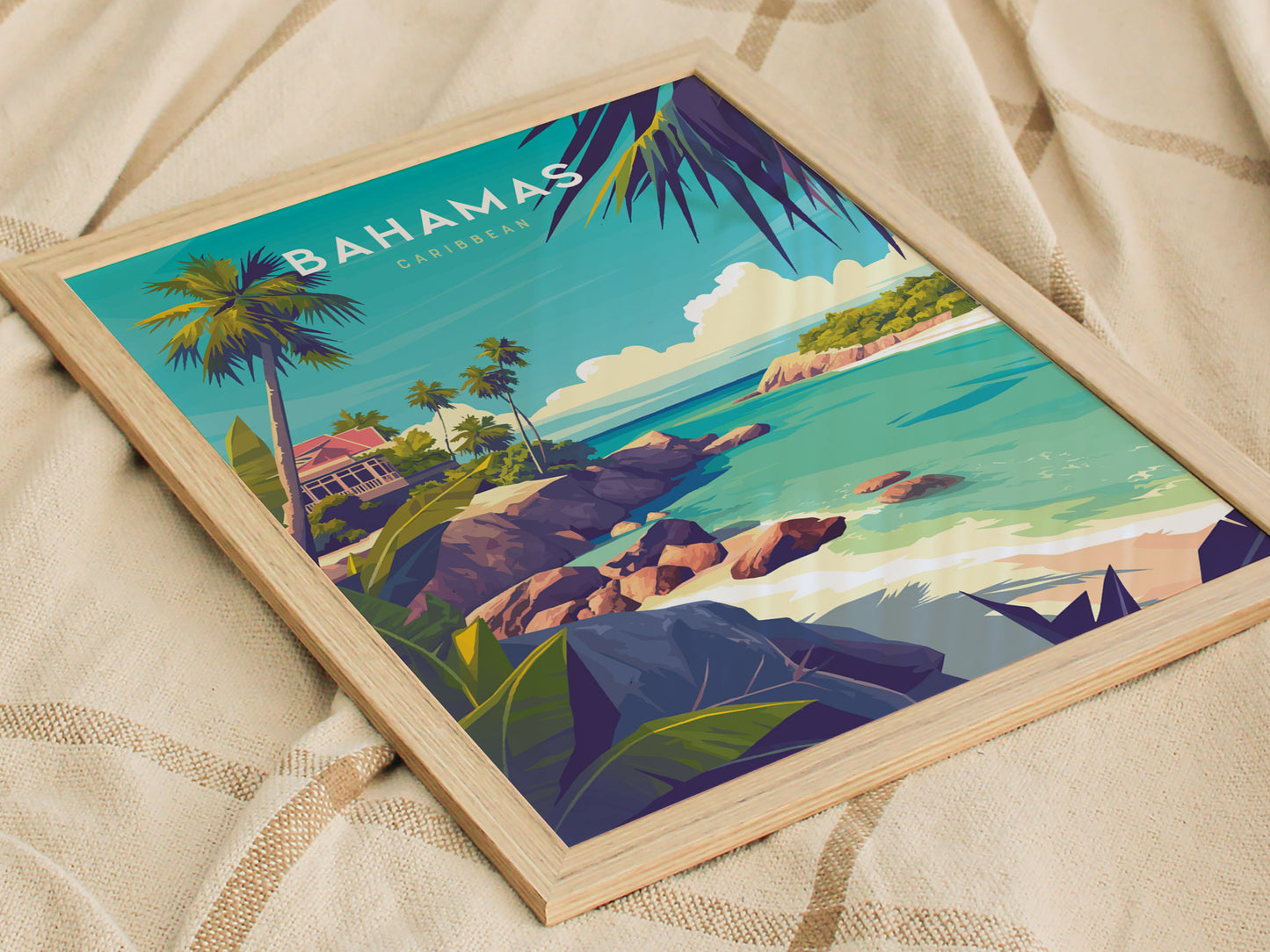 Framed illustration of a tropical beach scene with palm trees, turquoise waters, and rocky shores, titled Bahamas Caribbean, resting on a light-colored fabric background.