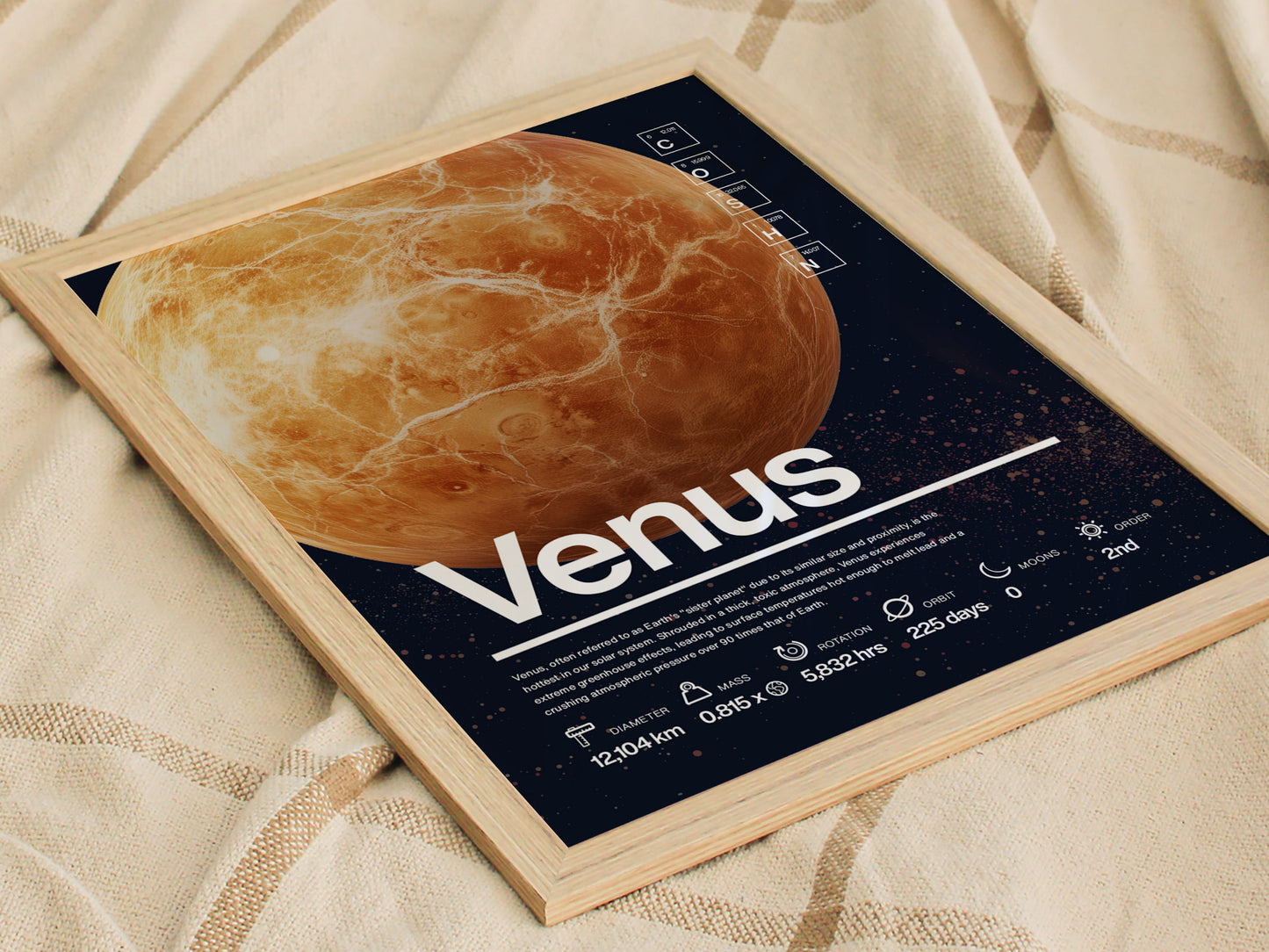 A framed Venus planet poster featuring scientific facts in Helvetica typography is displayed on a textured fabric. The poster highlights Venus with detailed illustrations and measurements.