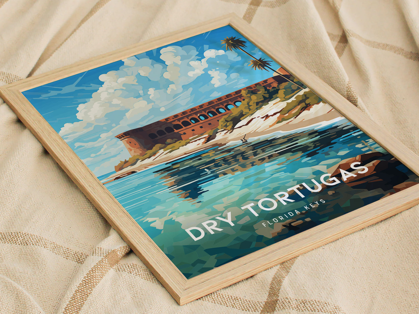A framed poster of Dry Tortugas National Park features Fort Jefferson against a vibrant blue sky and turquoise waters, lying on a patterned fabric surface.