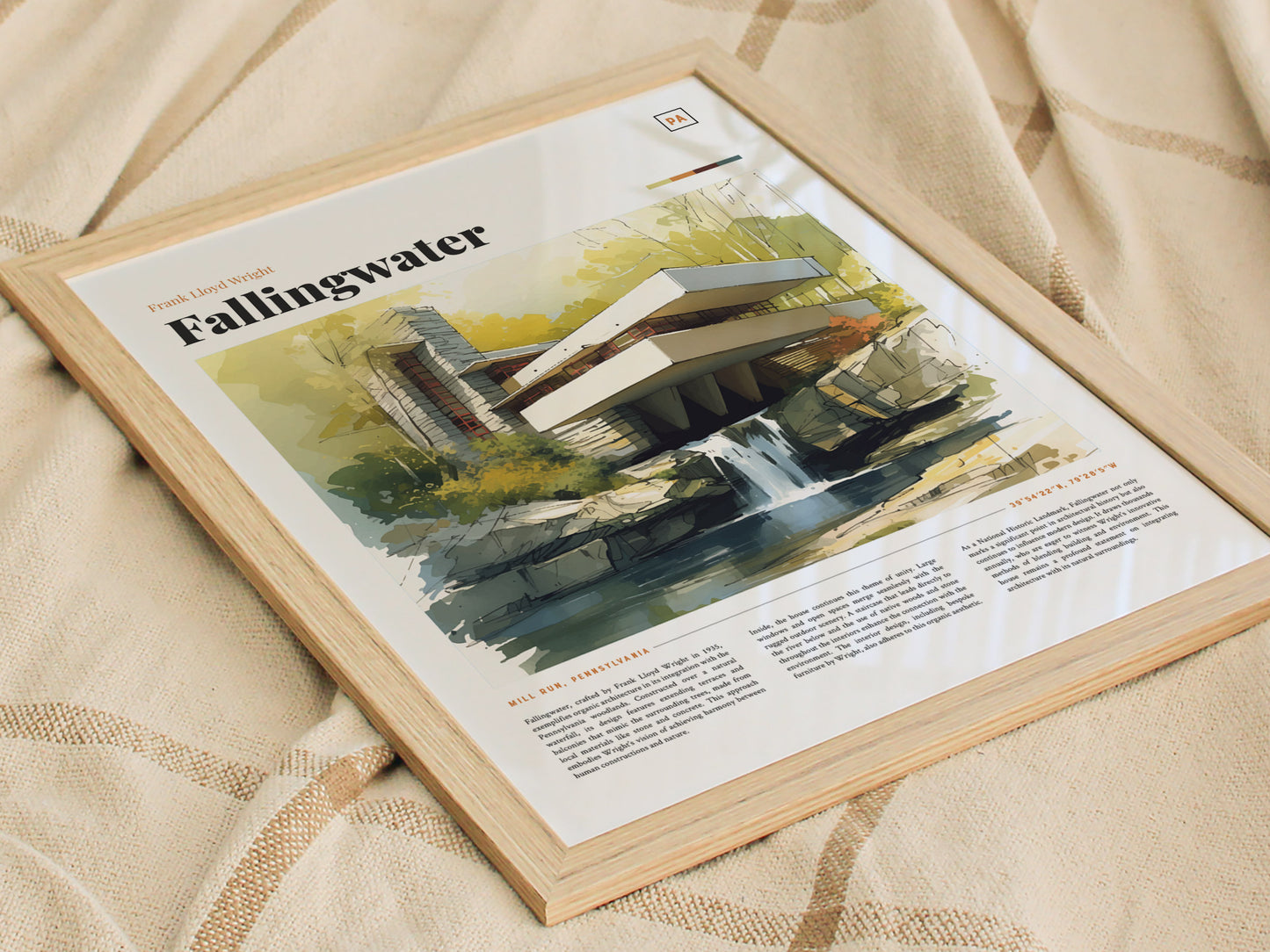 A framed poster of Frank Lloyd Wrights Fallingwater rests on a textured beige fabric. The watercolor illustration showcases the iconic architecture and surrounding nature in a modern design.