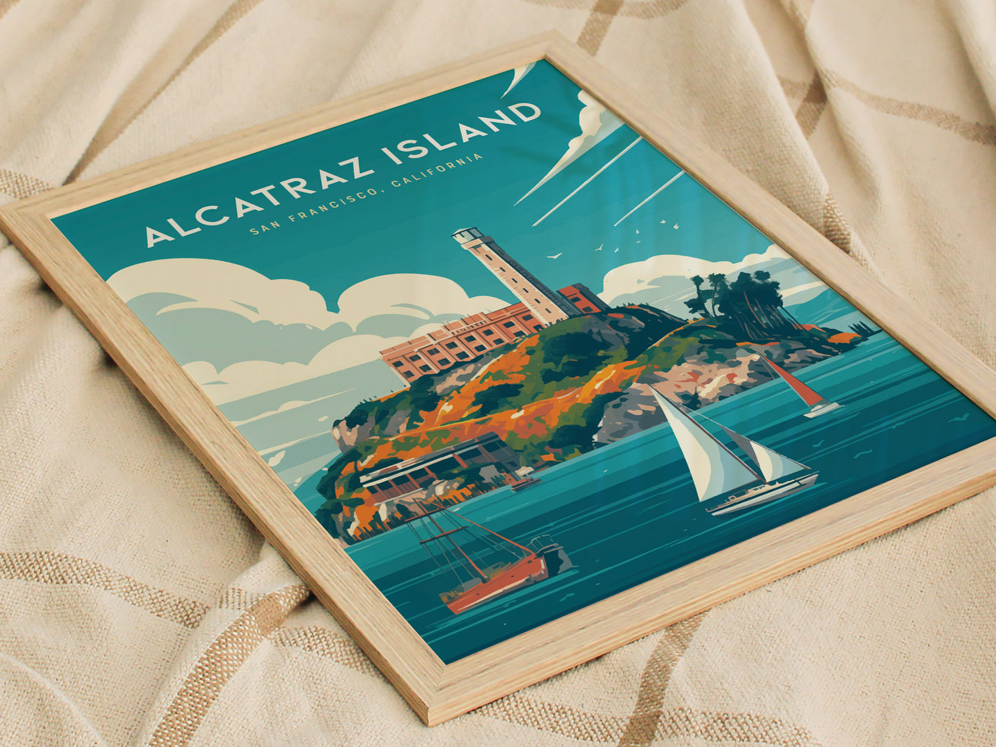 Framed poster of Alcatraz Island featuring the iconic prison, surrounded by sailboats on blue waters, set against a background of stylized clouds and a beige fabric.