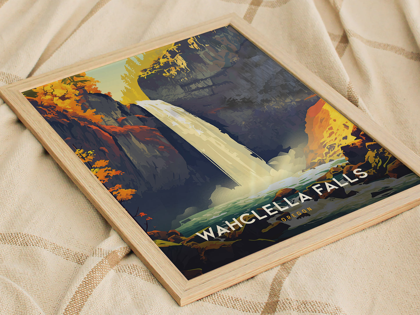 A framed poster of Wahclella Falls on a light fabric surface, featuring vibrant autumn foliage and a cascading waterfall in a scenic gorge.