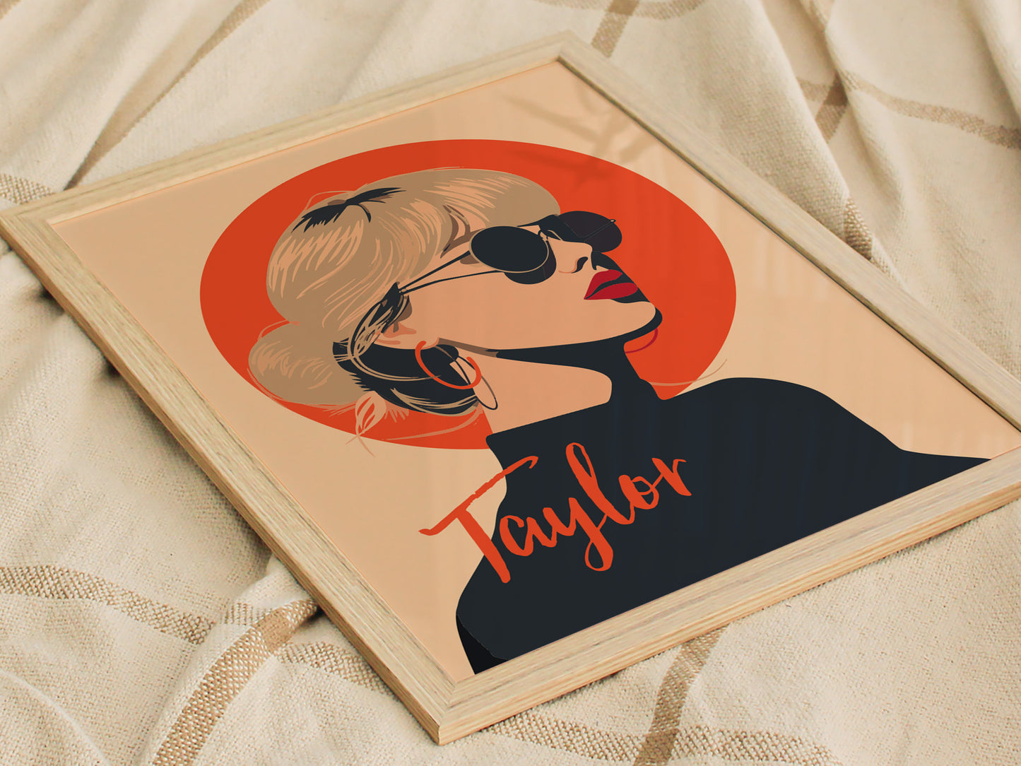 A framed poster featuring a minimalist illustration of a woman with sunglasses and a topknot, set against an orange circle. The word Taylor is written stylishly below.
