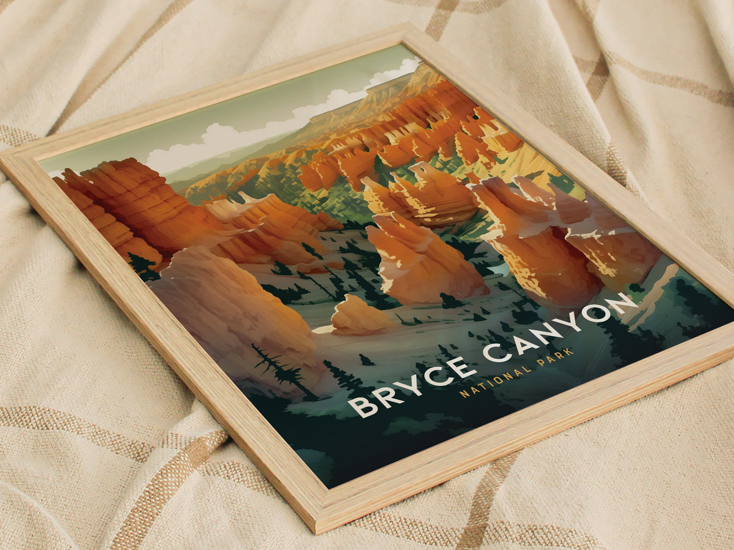 A framed print of Bryce Canyon National Park displays vibrant orange and red hoodoos under a cloudy sky, set against a beige cloth backdrop.