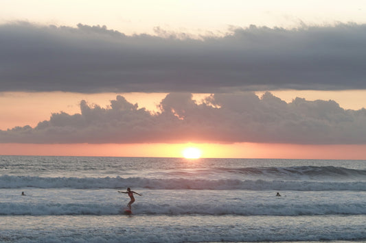 man surfing on beach during sunset