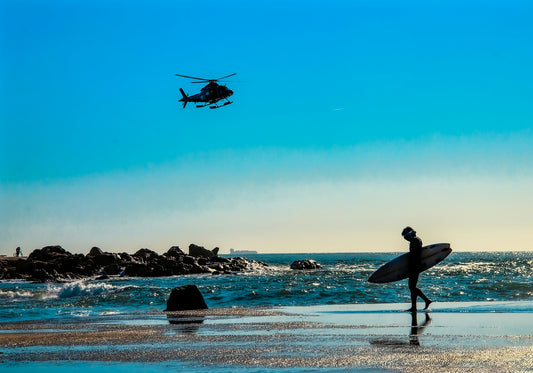 a man holding a surfboard while flying a helicopter
