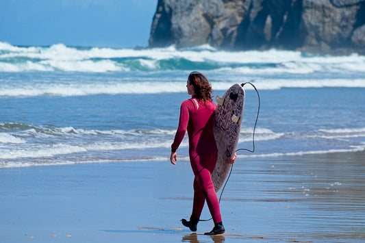 Surfer walks along the beach with their board.