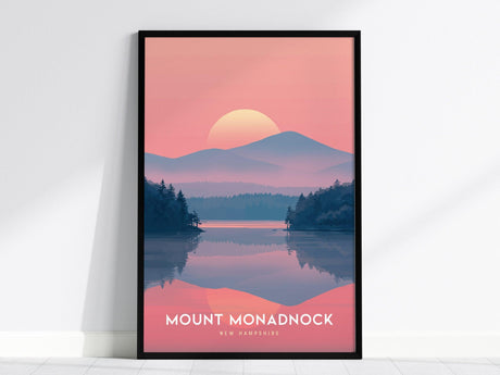 Framed poster of Mount Monadnock with a pink and purple sunset, reflecting over a calm lake surrounded by silhouetted pine trees. The text reads Mount Monadnock, New Hampshire.