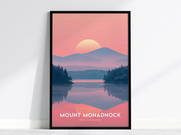 Framed poster of Mount Monadnock with a pink and purple sunset, reflecting over a calm lake surrounded by silhouetted pine trees. The text reads Mount Monadnock, New Hampshire.