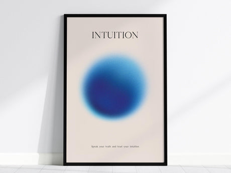 A framed poster features a soft blue gradient circle with the word INTUITION above it and a motivational phrase below. The background is a light, neutral color.