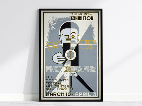 Art Deco poster featuring a stylized photographer with a vintage camera, promoting the Sioux City Camera Clubs Second Annual Exhibition. Includes bold typography and geometric shapes in a framed design.