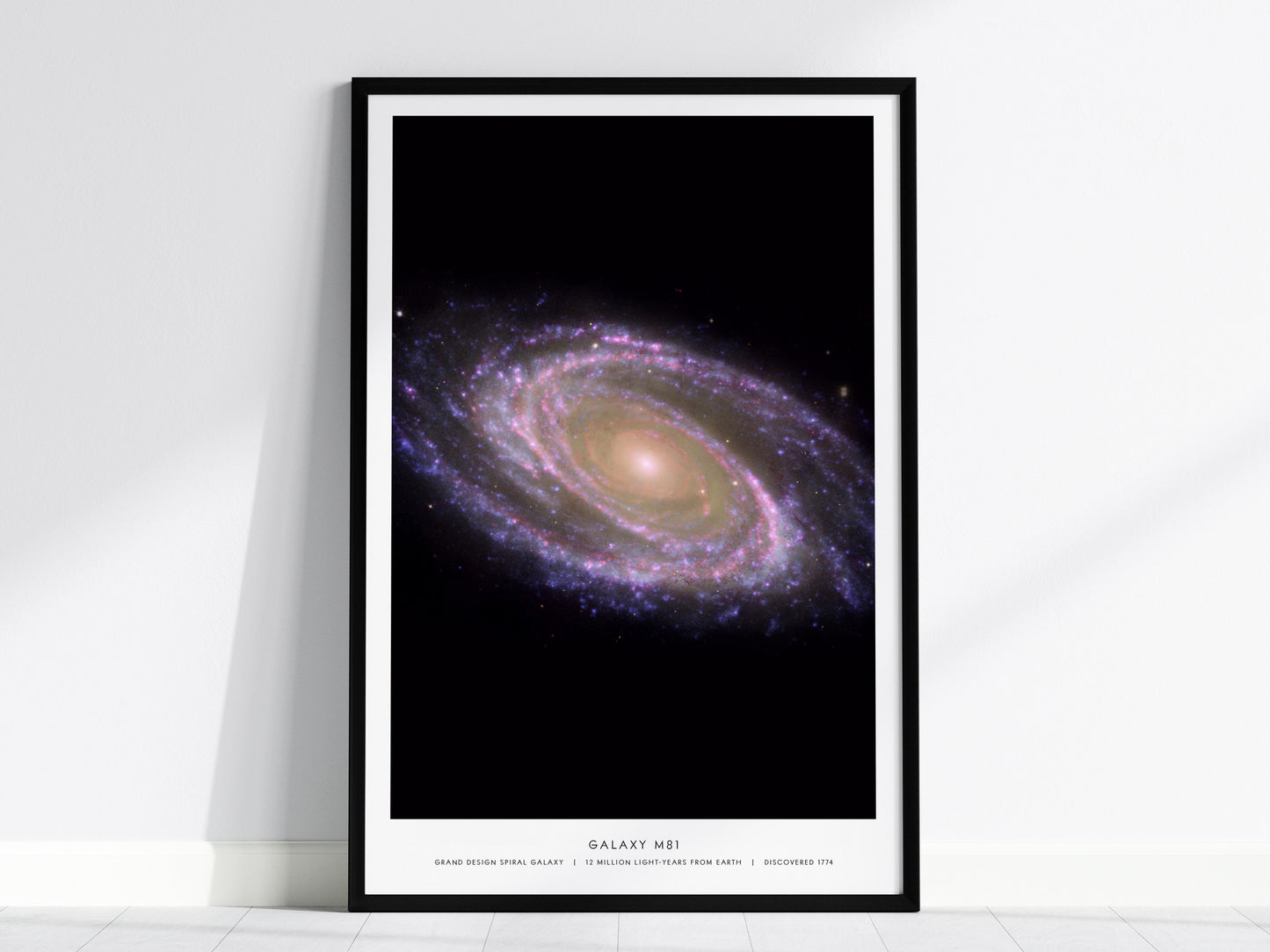 Black framed M81 galaxy poster centered over a sofa in a modern home interior
