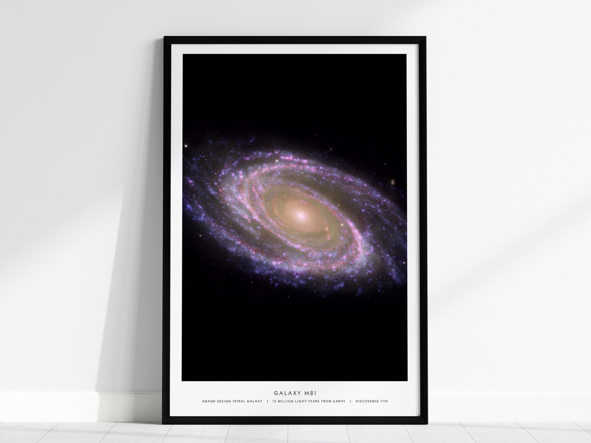 Black framed M81 galaxy poster centered over a sofa in a modern home interior