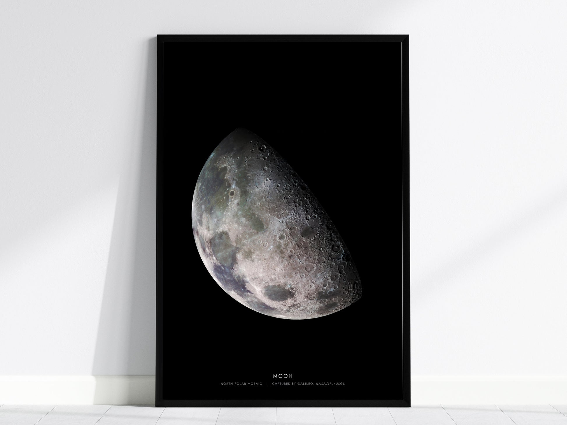 Black framed print of the moon's surface on a white wall