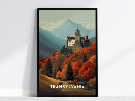 A framed poster depicts a dramatic hilltop castle surrounded by vibrant autumn forests and layered mountain silhouettes. The text Transylvania Romania is visible at the bottom, enhancing the travel-poster style.