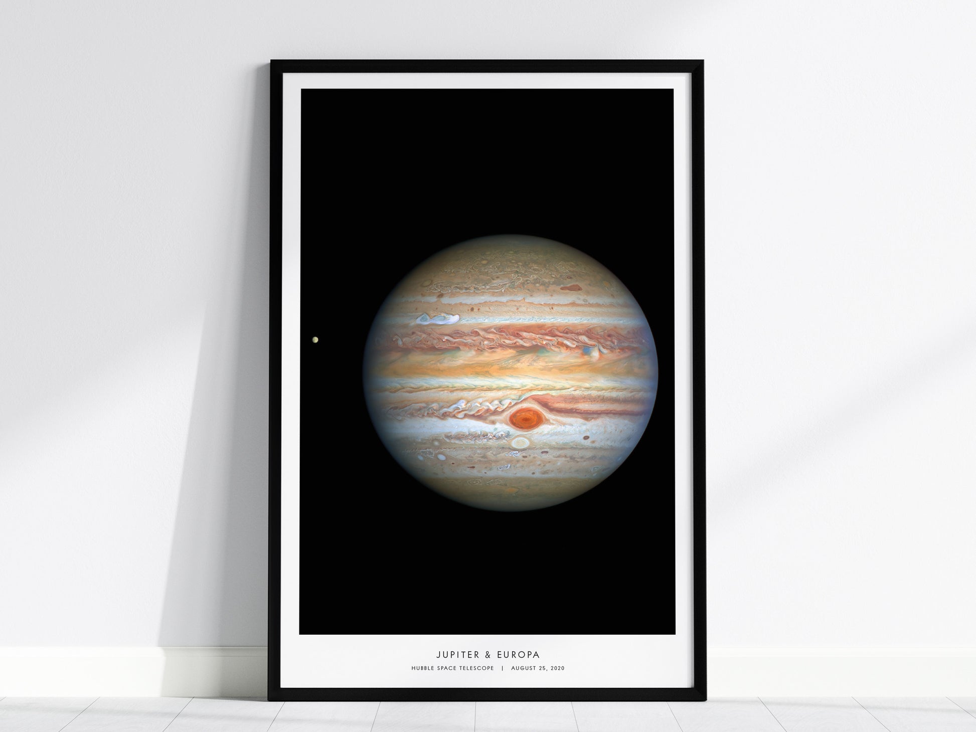 Framed poster of Jupiter with Europa, on a white wall.