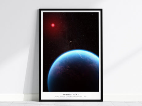 A framed poster, wall art featuring the exoplanet K2-18 b, shows a vibrant blue planet against a starry background with a distant red star. The artwork is displayed on a white wall, leaning slightly against it.
