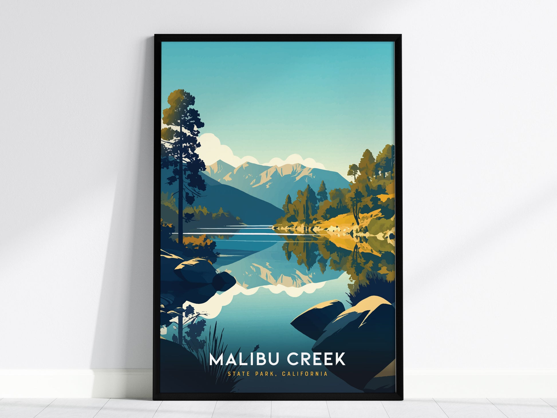A framed poster depicting a serene landscape with mountains, trees, and a reflective lake under a clear blue sky, titled Malibu Creek State Park, California.