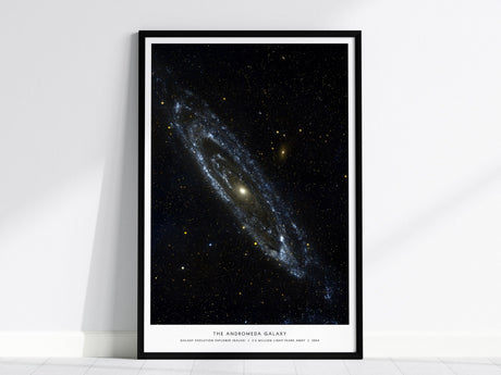 Black framed Andromeda Galaxy poster centered over a sofa with minimalist home decor