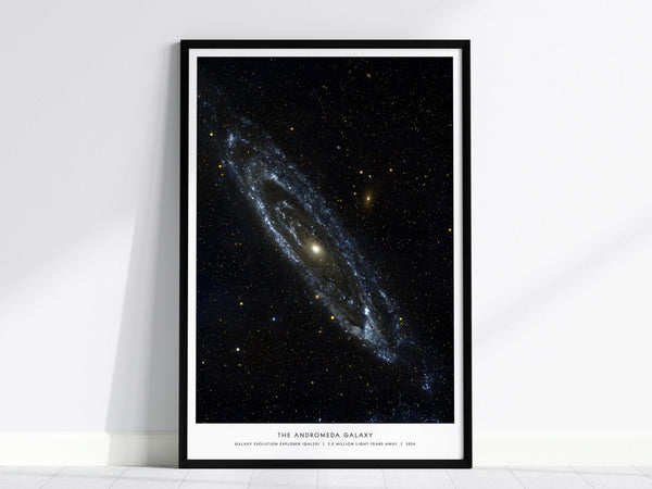 Black framed Andromeda Galaxy poster centered over a sofa with minimalist home decor