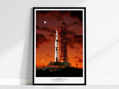 Black framed Apollo 4 launch poster centered over a sofa with minimalist home decor