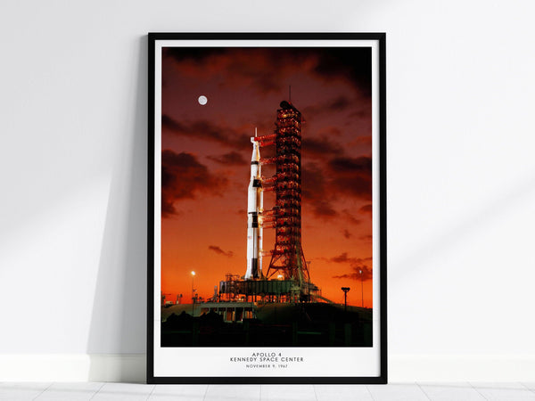 Black framed Apollo 4 launch poster centered over a sofa with minimalist home decor