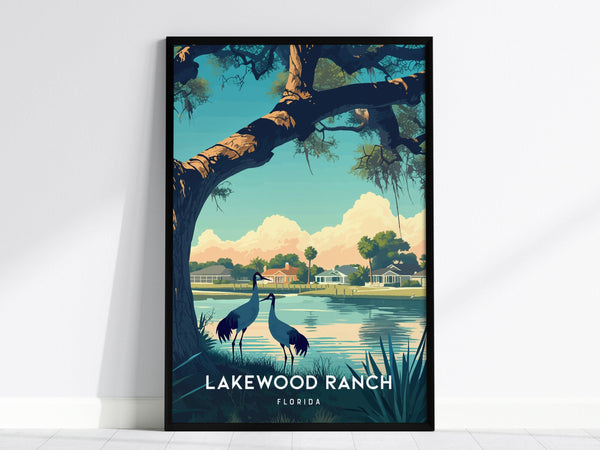 A framed poster depicting a serene lakeside scene with two cranes, a large tree, and houses in the background under a blue sky labeled Lakewood Ranch Florida.