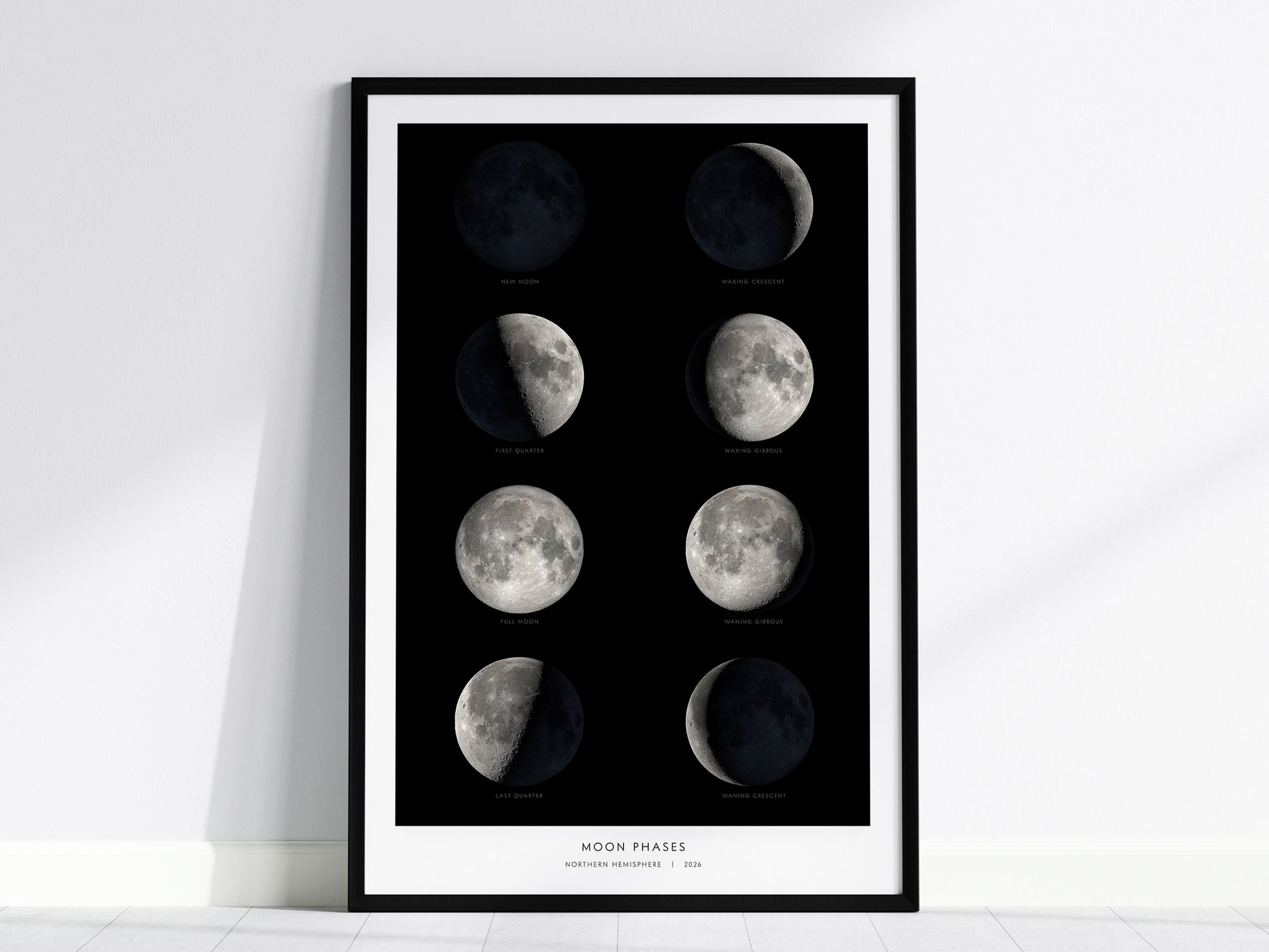 A framed poster displaying the eight phases of the Moon, arranged in two rows. Each phase, from new moon to waning crescent, is depicted in detailed grayscale against a black background, with labels for each phase.