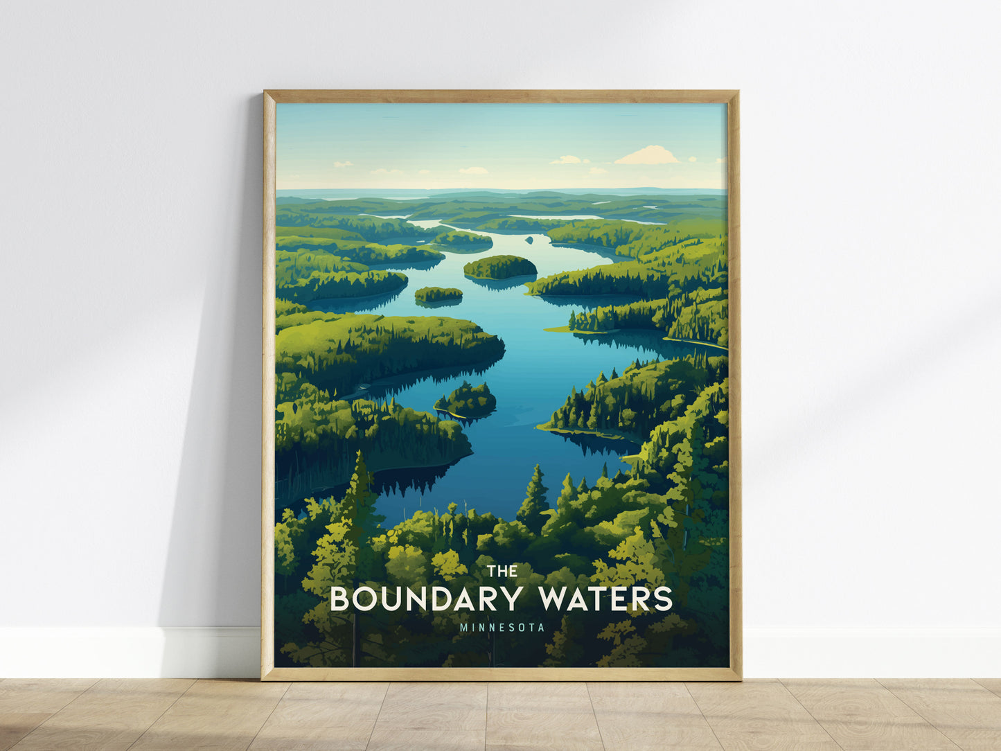 Framed poster depicting a serene landscape of interconnected lakes and lush green forests under a blue sky, titled The Boundary Waters Minnesota, leaning against a white wall.