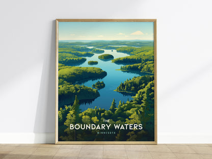 Framed poster depicting a serene landscape of interconnected lakes and lush green forests under a blue sky, titled The Boundary Waters Minnesota, leaning against a white wall.