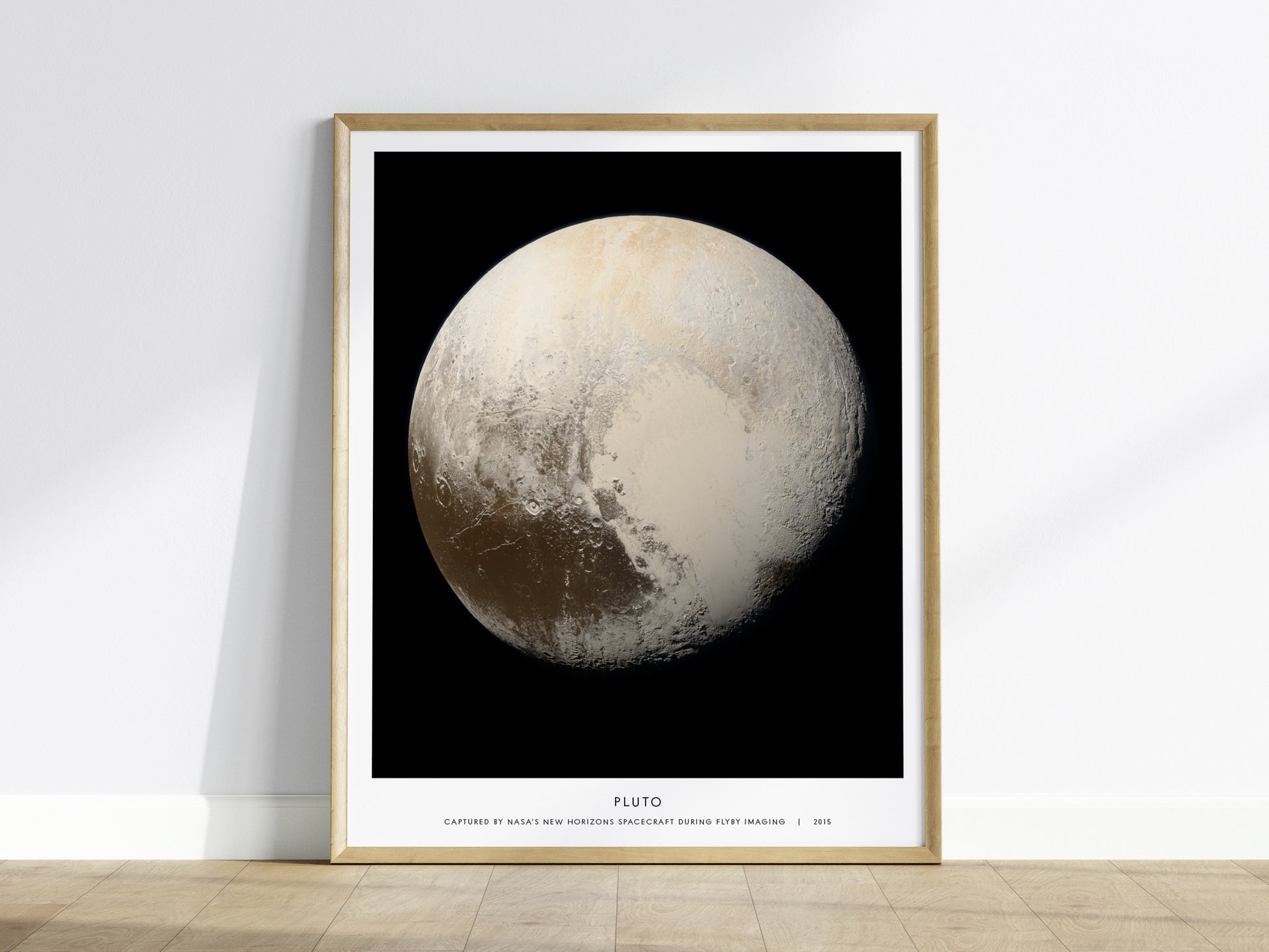 Framed poster of Pluto with a black background on a wooden floor.