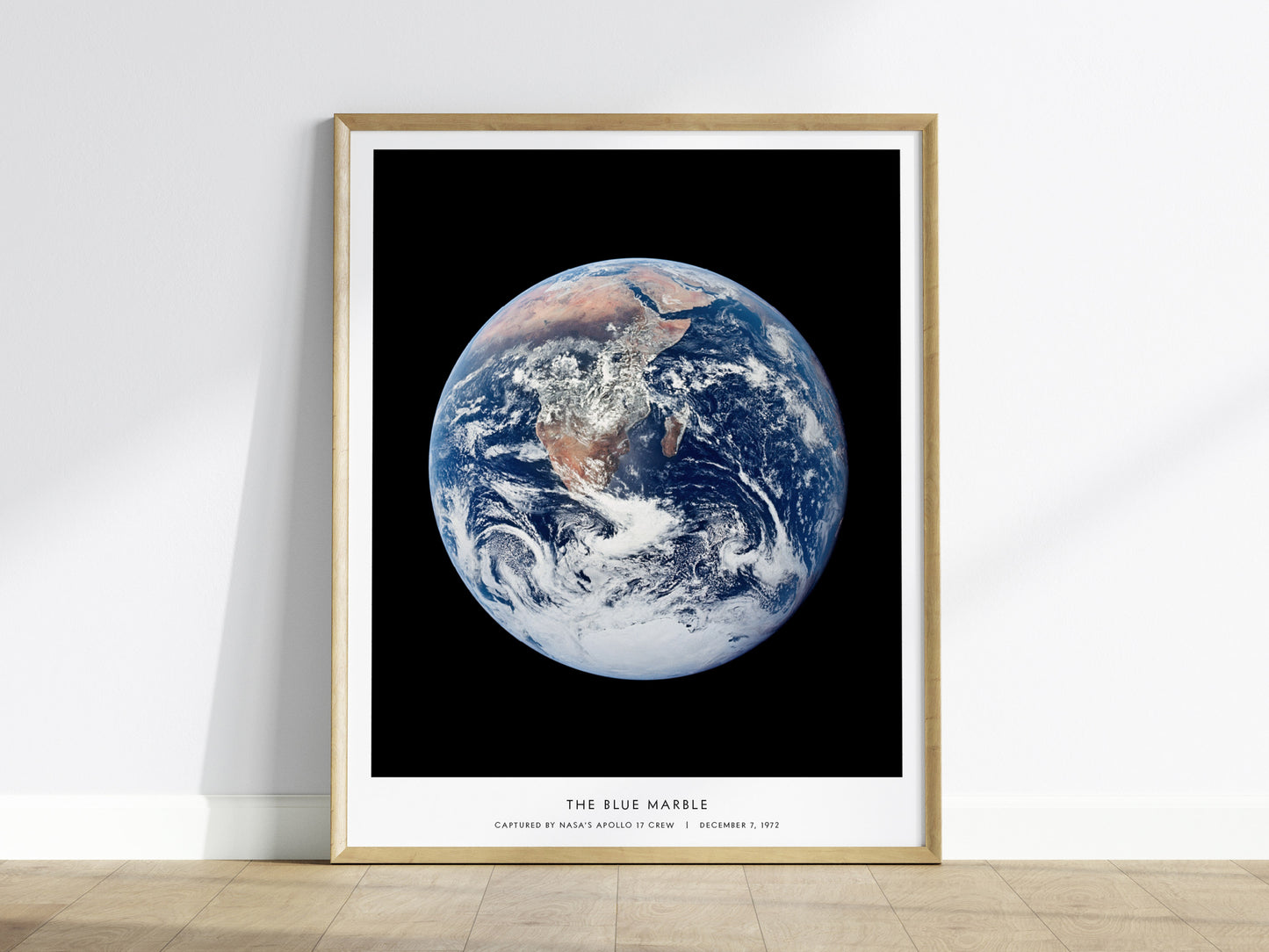 Framed Blue Marble Earth poster centered on a white wall minimalist home decor